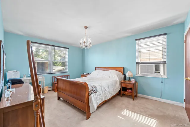 a bedroom with a bed chandelier and a window