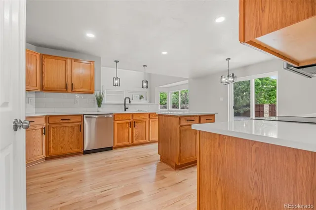 a large kitchen with stainless steel appliances granite countertop a sink a counter space and wooden floor