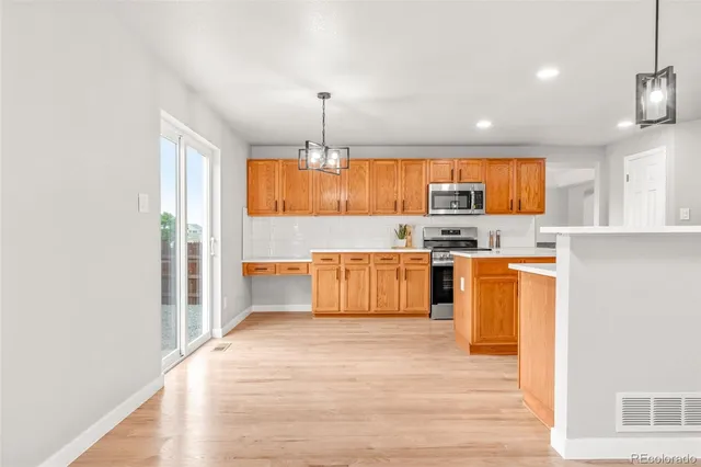 a kitchen with stainless steel appliances granite countertop a stove top oven a sink dishwasher and a refrigerator with wooden floor