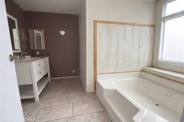 a spacious bathroom with a tub sink and mirror