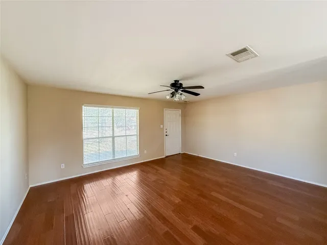 an empty room with windows and ceiling fan