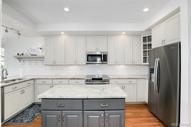 a kitchen with granite countertop a refrigerator sink and white cabinets