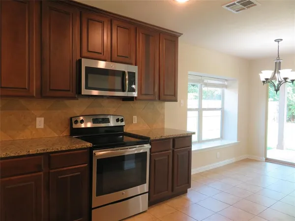 a kitchen with granite countertop wooden cabinets and stainless steel appliances