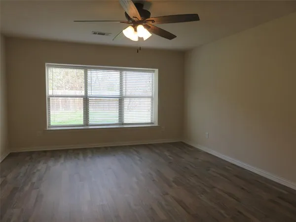 an empty room with wooden floor fan and windows