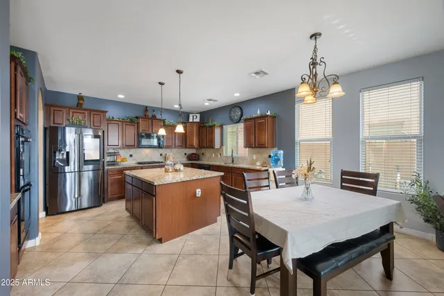 a kitchen with a stove a refrigerator a sink dishwasher with a dining table and chairs