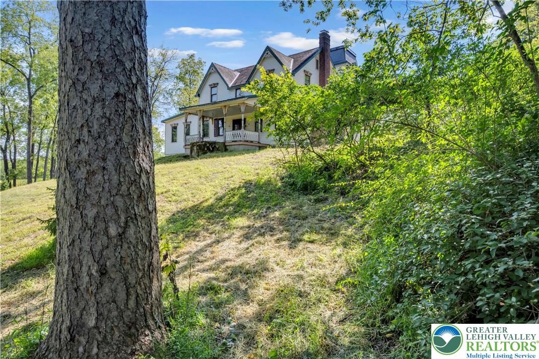 384 Henry Road Nazareth, PA 18064 - Photo 1 of 54 An elegant multi-story home sits atop a grassy slope, framed by mature trees.