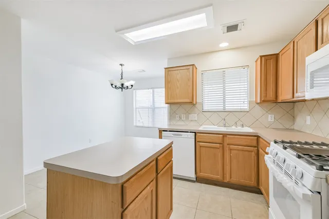 a kitchen with a sink dishwasher a stove and white cabinets