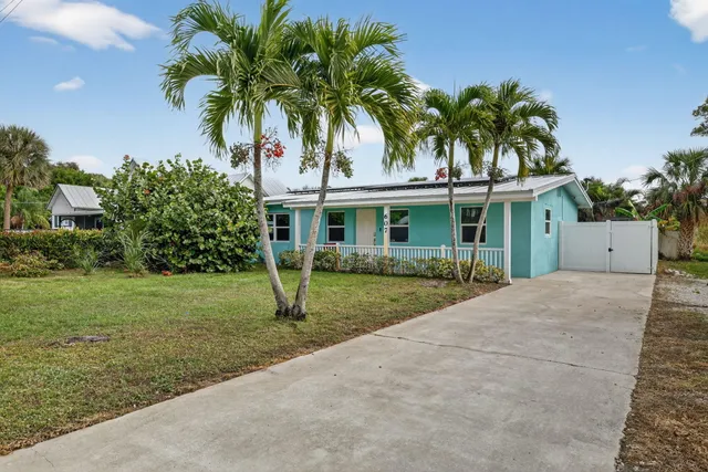 front view of a house with a yard and palm trees