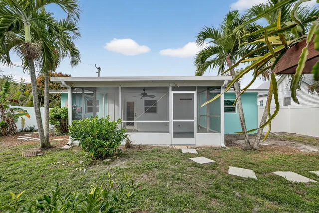a view of a house with a yard and palm trees