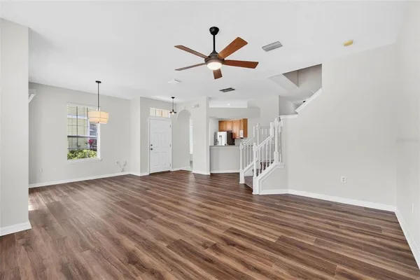 a view of an empty room with wooden floor and a ceiling fan