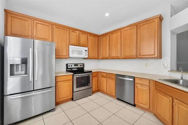 a kitchen with stainless steel appliances granite countertop a refrigerator stove top oven and sink