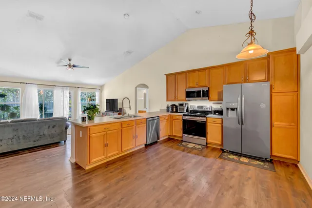 a kitchen with granite countertop a refrigerator a stove top oven and white cabinets with wooden floor