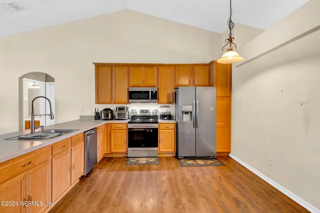 a kitchen with stainless steel appliances granite countertop a sink cabinets a refrigerator and a stove