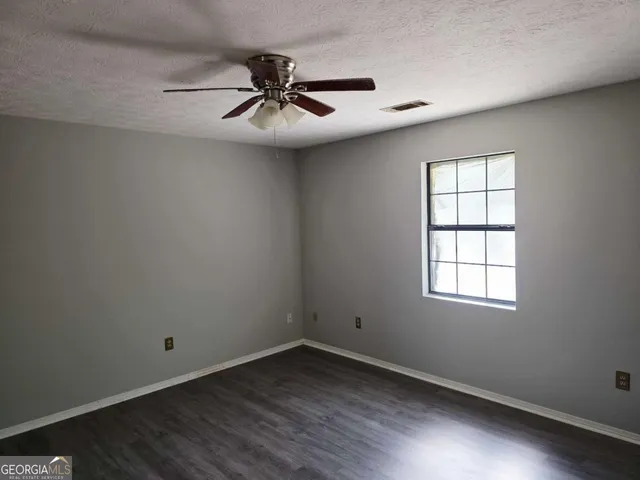 an empty room with a window and a fan