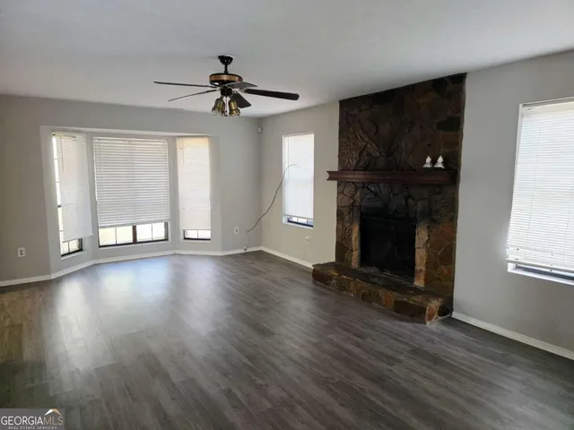 an empty room with wooden floor fireplace and windows