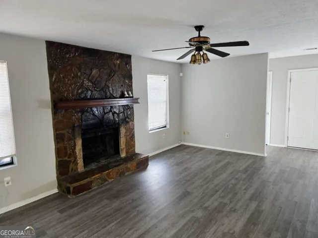 a view of a livingroom with wooden floor a fireplace and a window