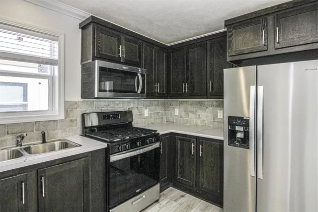 a kitchen with granite countertop a refrigerator stove and microwave