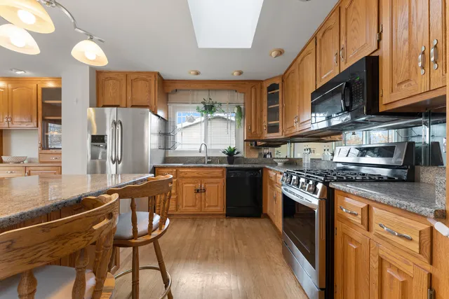 a kitchen with stainless steel appliances granite countertop wooden cabinets a stove top oven a sink and dishwasher