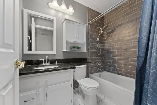 a bathroom with a granite countertop sink a toilet and bathtub