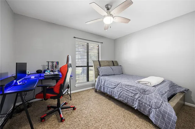a bedroom with a bed a desk and chair with a bookshelf