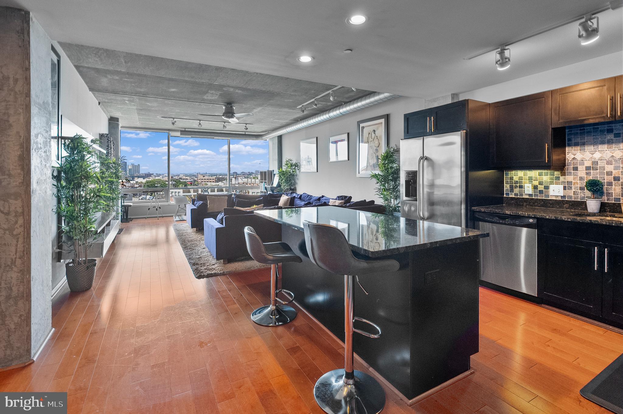 1200 Steuart Street, Unit 530 Baltimore, MD 21230 - Photo 5 of 38 a living room with stainless steel appliances kitchen island granite countertop a table chairs and a wooden floors
