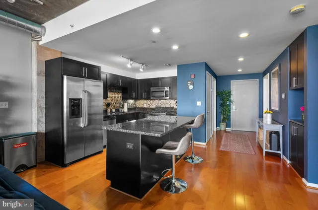 a kitchen with stainless steel appliances granite countertop a refrigerator dining table and chairs