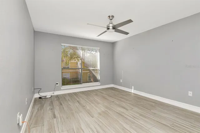 a view of an empty room with wooden floor and a window