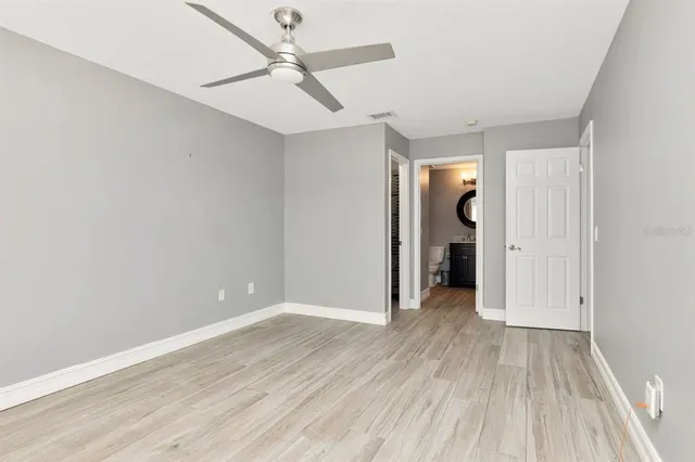 an empty room with wooden floor and ceiling fan