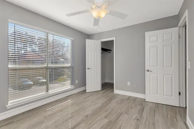 a view of empty room with wooden floor and fan