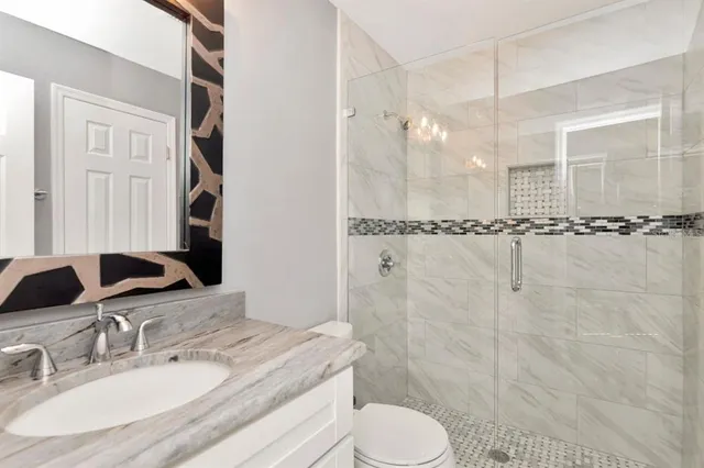 a bathroom with a granite countertop sink toilet a mirror a shower and a bathtub