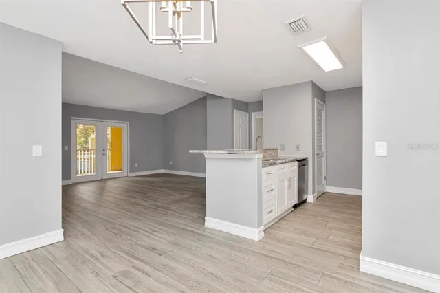 a view of kitchen and empty room with wooden floor