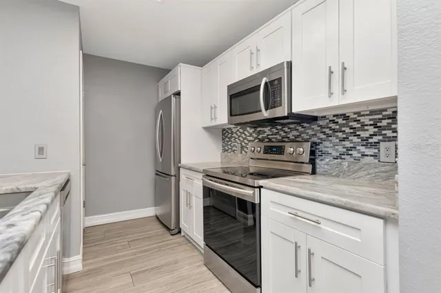 a kitchen with stainless steel appliances white cabinets and a stove top oven