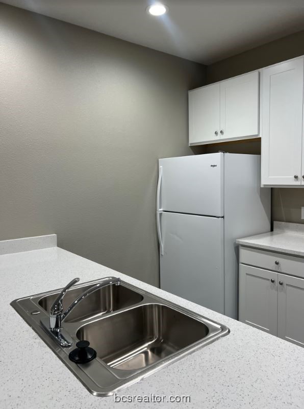1305 West Villa Maria Road, Unit D105 Bryan, TX 77801 - Photo 6 of 20 a kitchen with a refrigerator and white cabinets