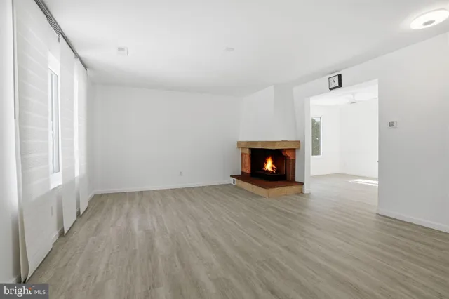 a room with wooden floor a fireplace and window