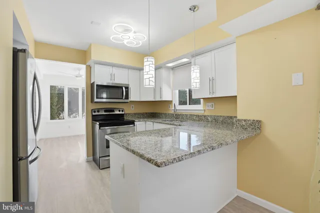 a kitchen with stainless steel appliances granite countertop a sink a microwave and a refrigerator