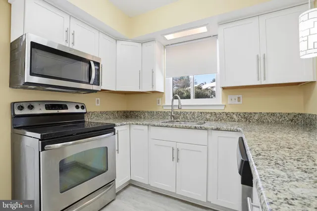 a kitchen with granite countertop white cabinets stainless steel appliances and a sink