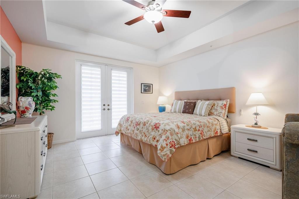 14565 Red Fox Run, Unit 613 Naples, FL 34110 - Photo 17 of 48 a spacious bedroom with a bed and a chandelier