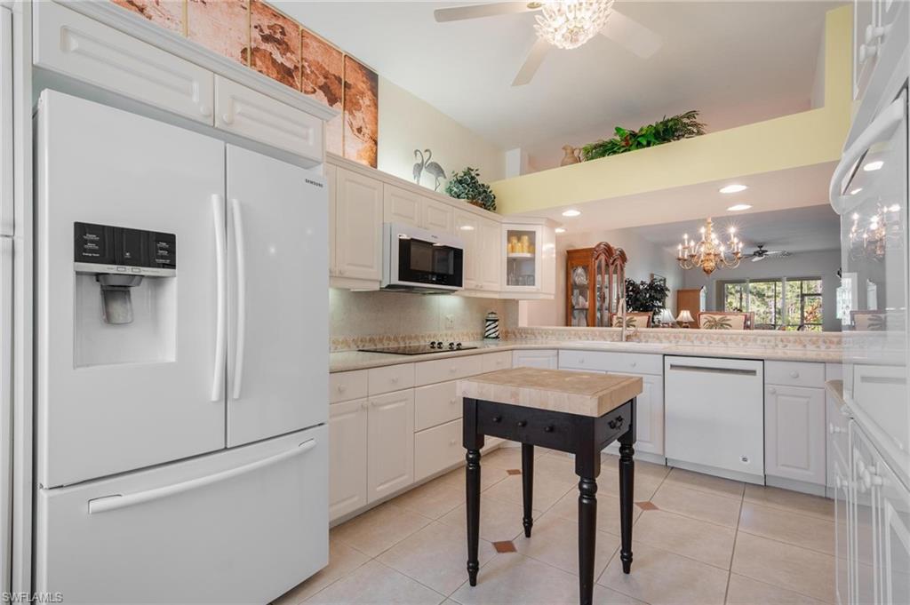 14565 Red Fox Run, Unit 613 Naples, FL 34110 - Photo 5 of 48 a kitchen with stainless steel appliances granite countertop a refrigerator a stove and white cabinets with wooden floor