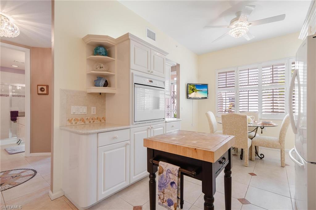 14565 Red Fox Run, Unit 613 Naples, FL 34110 - Photo 8 of 48 a kitchen with stainless steel appliances cabinets a dining table and chairs