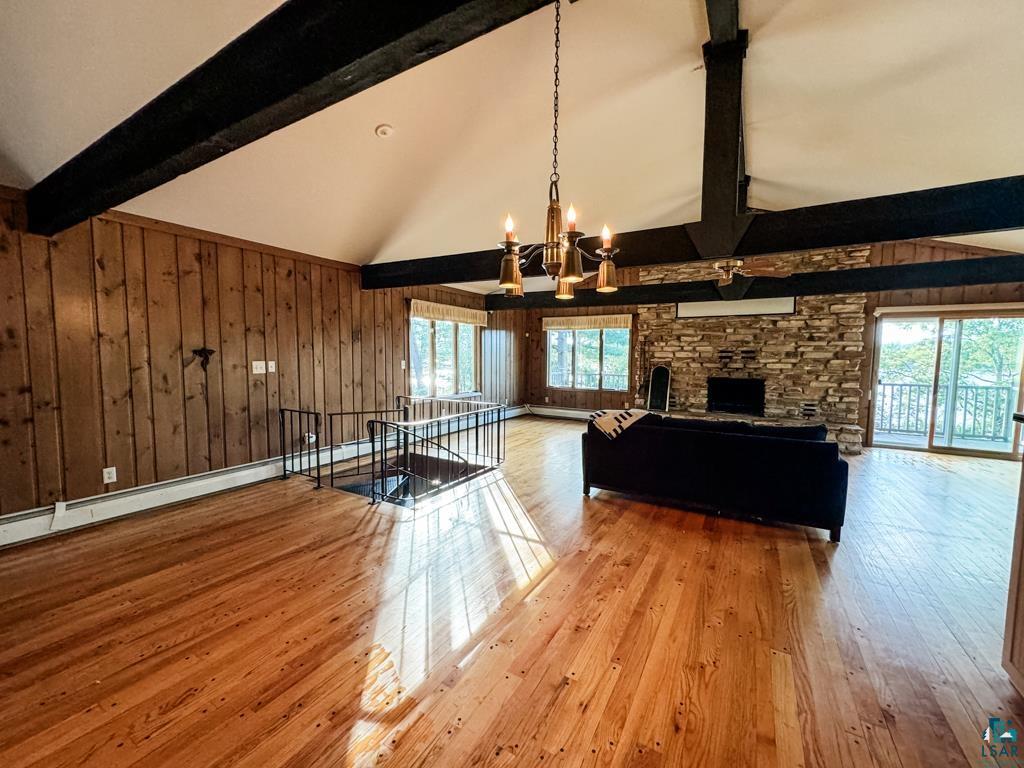 N13431 County Line Road Minong, WI 54859 - Photo 15 of 42 Unfurnished living room featuring a healthy amount of sunlight, a fireplace, light hardwood / wood-style flooring, and beamed ceiling