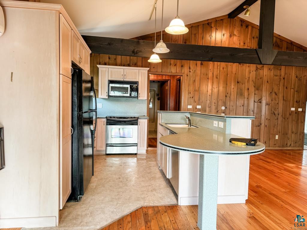N13431 County Line Road Minong, WI 54859 - Photo 17 of 42 Kitchen featuring hanging light fixtures, light hardwood / wood-style flooring, wooden walls, black appliances, and lofted ceiling with beams