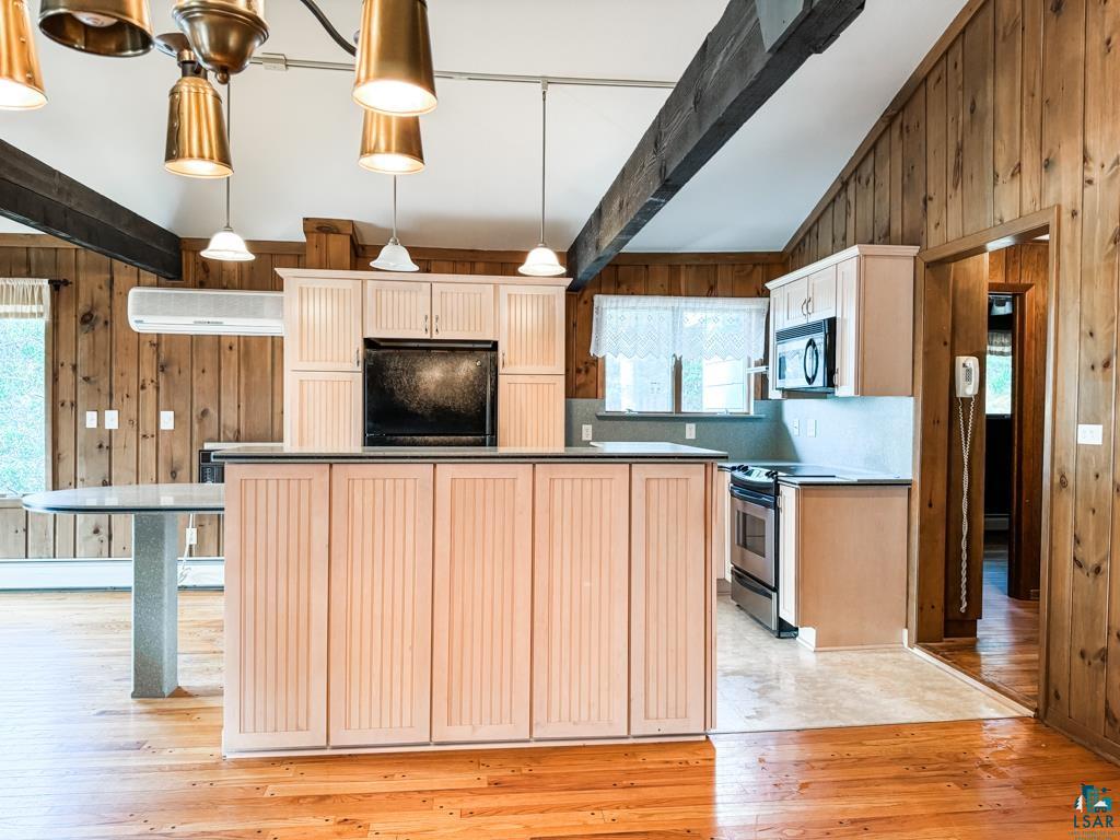 N13431 County Line Road Minong, WI 54859 - Photo 18 of 42 Kitchen featuring appliances with stainless steel finishes, wooden walls, light wood-type flooring, and beamed ceiling