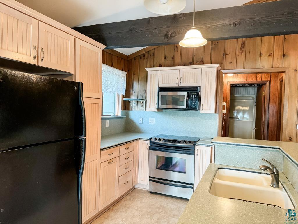 N13431 County Line Road Minong, WI 54859 - Photo 20 of 42 Kitchen featuring lofted ceiling with beams, sink, wood walls, black appliances, and decorative light fixtures