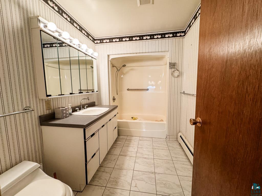 N13431 County Line Road Minong, WI 54859 - Photo 21 of 42 Full bathroom featuring vanity, washtub / shower combination, toilet, and a baseboard heating unit