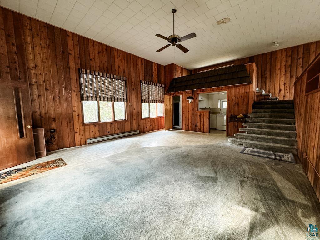 N13431 County Line Road Minong, WI 54859 - Photo 36 of 42 Unfurnished living room featuring a baseboard radiator, carpet, ceiling fan, and wood walls