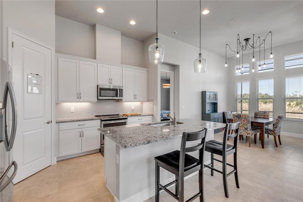246 Azure Mist Way Daytona Beach, FL 32124 - Photo 7 of 33 a kitchen with stainless steel appliances granite countertop a kitchen island a stove a table and chairs in it