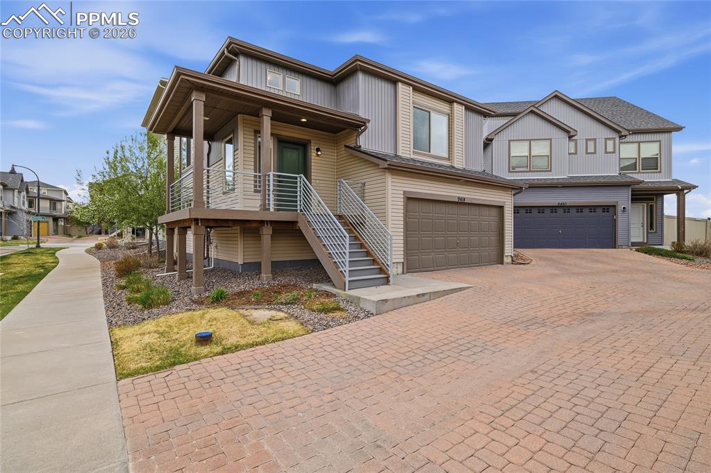View of front of property featuring an attached garage, decorative driveway, a porch, and a residential view