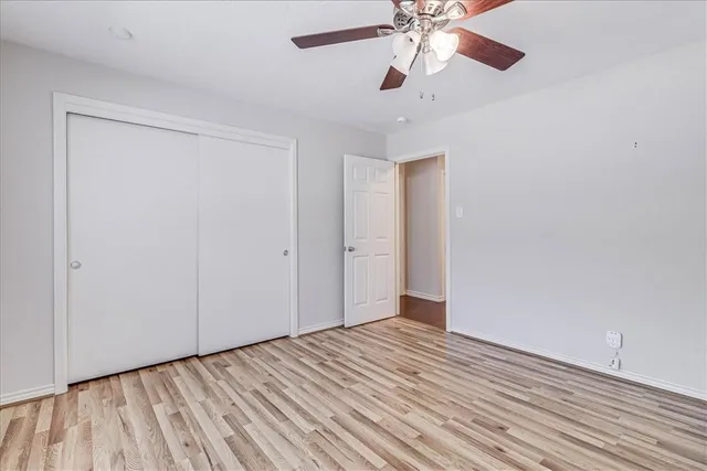 wooden floor in an empty room with a chandelier fan