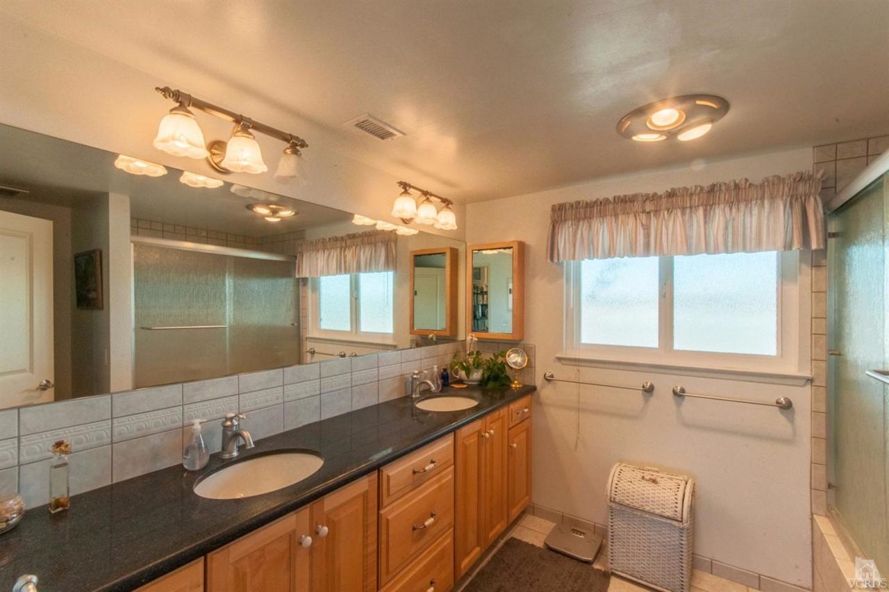 5241 Beachcomber Street Oxnard, CA 93035 - Photo 16 of 21 a bathroom with a granite countertop sink a large mirror and a shower