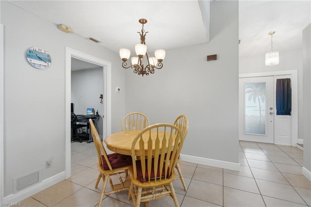3022 47th Street Southwest Naples, FL 34116 - Photo 19 of 46 Tile flooring extending through an open doorway, featuring a ceiling-mounted chandelier